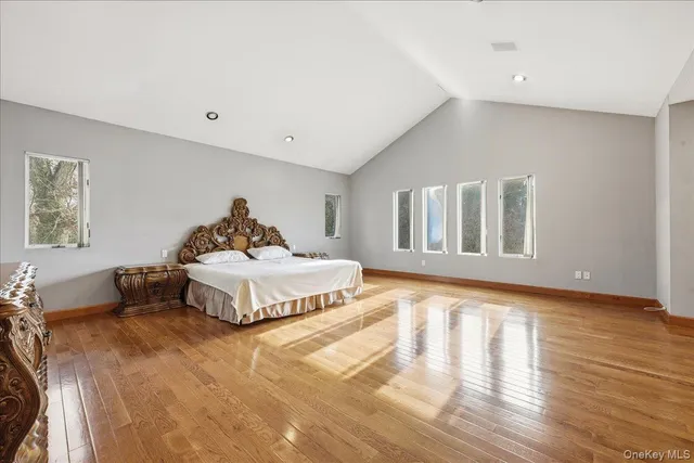 a spacious bedroom with a bed and wooden floor