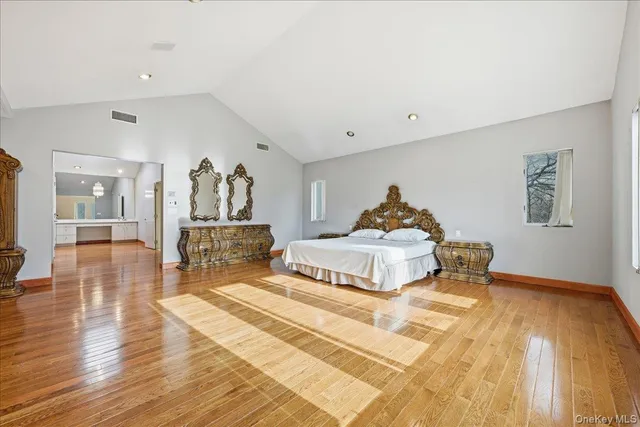 a spacious bedroom with a bed and wooden floor