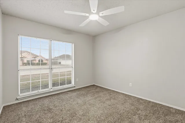 an empty room with closet and a ceiling fan