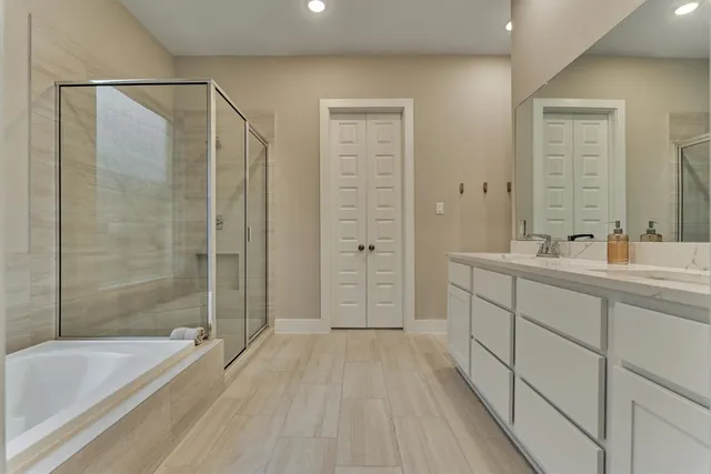 a bathroom with a double vanity sink a large mirror a shower and bathtub