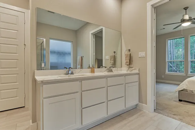 a bathroom with a double vanity sink mirror and next to a window
