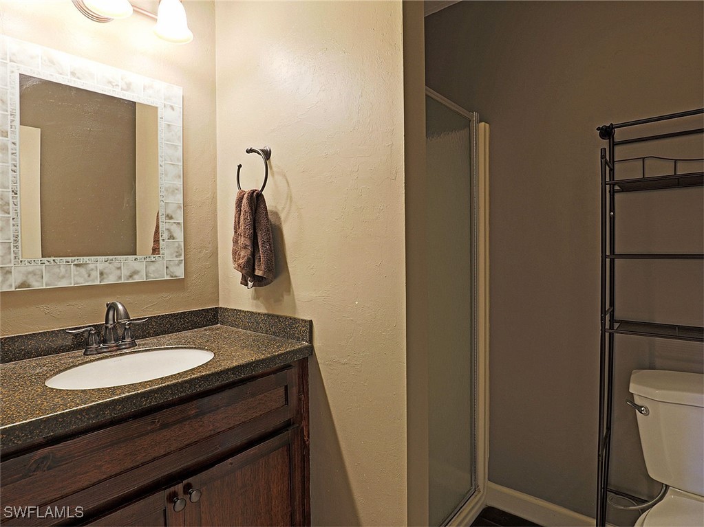 5804 Newfoundland Fort, Unit 1 Fort Myers, FL 33907 - Photo 24 of 29 a bathroom with a granite countertop sink toilet and mirror
