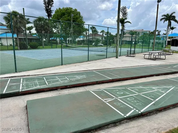 a view of a tennis ground with large trees