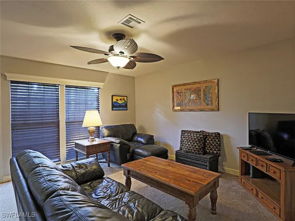 a living room with furniture a flat screen tv and a ceiling fan