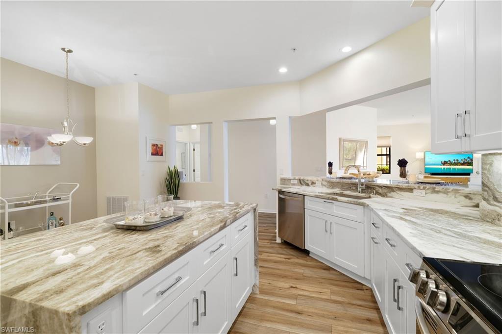 3787 Costa Maya Way, Unit 101 Estero, FL 33928 - Photo 17 of 49 Kitchen featuring white cabinets, stainless steel appliances, light stone countertops, light wood finished floors, and pendant lighting