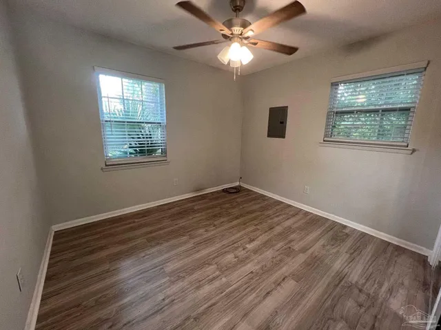 a view of empty room with wooden floor and fan