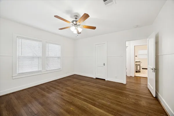 an empty room with wooden floor closet and windows
