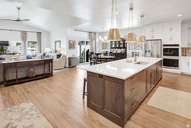 910 South 1700 West Layton, UT 84041 - Photo 7 of 26 Kitchen with two tone color scheme, a ceiling fan, light wood-style flooring, stainless steel fridge, and multiple ovens