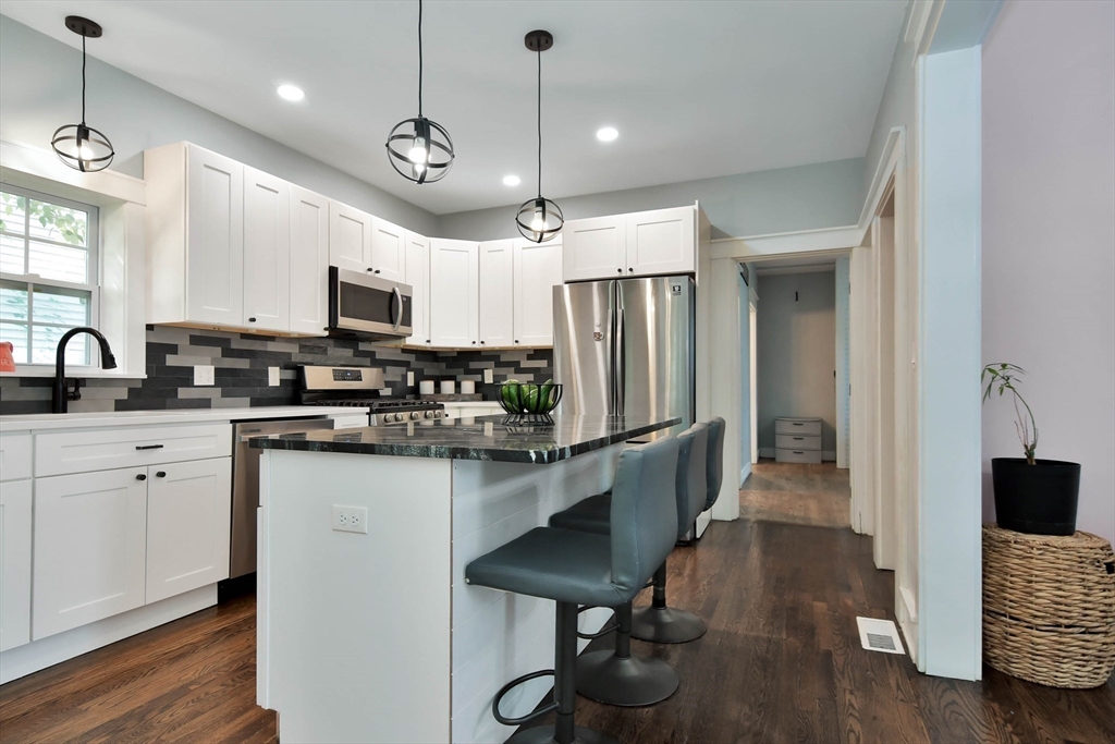 15 Balcomb Street Salem, MA 01970 - Photo 5 of 42 a kitchen with stainless steel appliances granite countertop a refrigerator a stove a sink dishwasher a oven a dining table and chairs with wooden floor