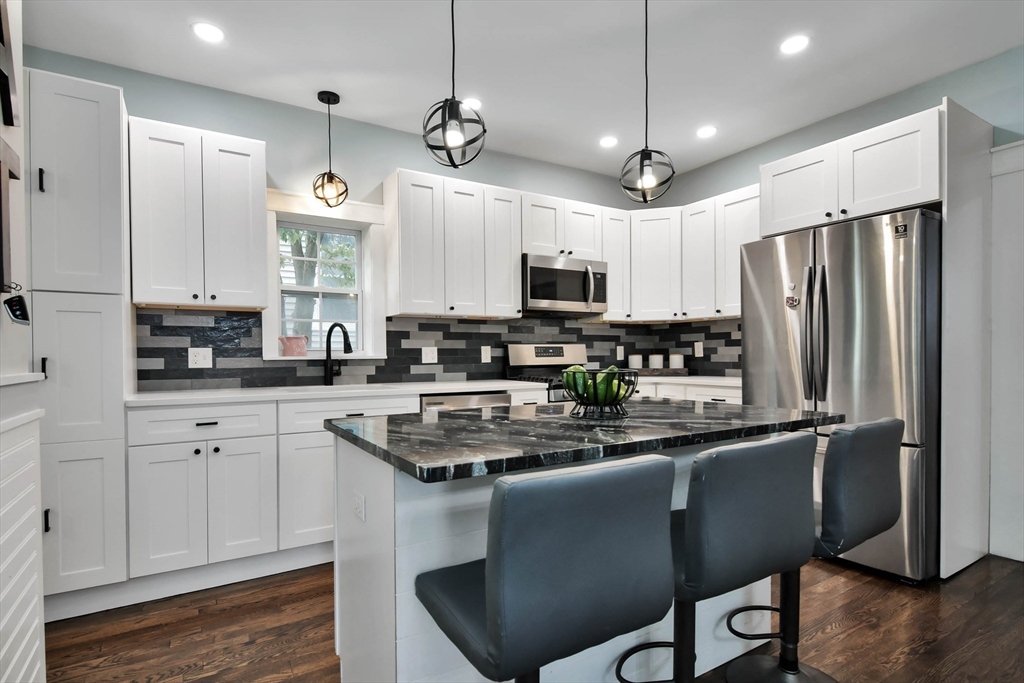 15 Balcomb Street Salem, MA 01970 - Photo 6 of 42 a kitchen with stainless steel appliances granite countertop a sink a stove a refrigerator cabinets and wooden floor
