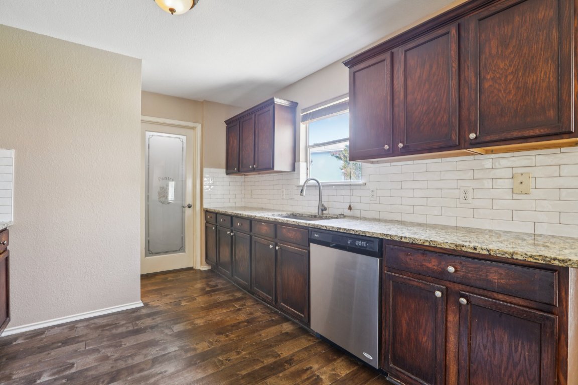 1132 Pine Portage Loop Leander, TX 78641 - Photo 11 of 39 a kitchen with granite countertop wooden cabinets a sink and dishwasher