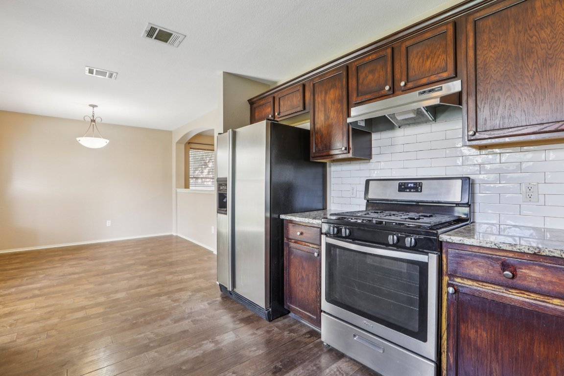 1132 Pine Portage Loop Leander, TX 78641 - Photo 12 of 39 a kitchen with stainless steel appliances granite countertop a stove and a refrigerator