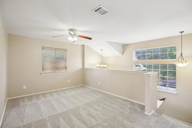 an empty room with windows and fan