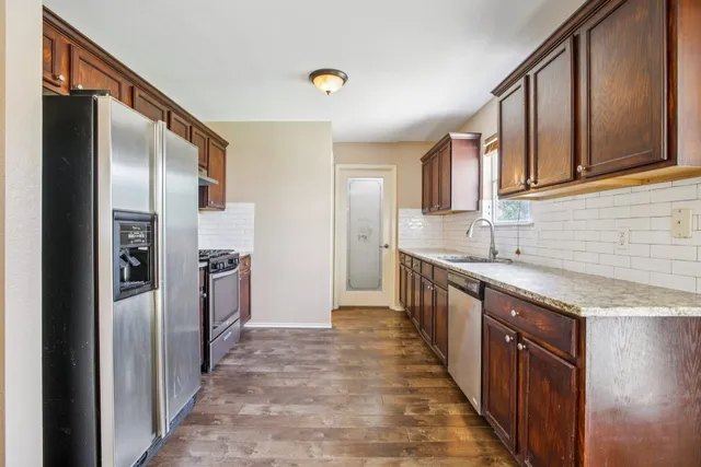 a kitchen with granite countertop wooden cabinets a sink and dishwasher