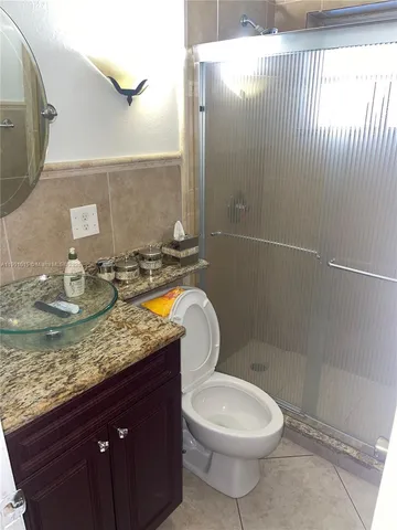 a bathroom with a granite countertop toilet sink and mirror
