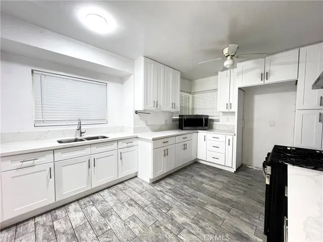 a kitchen with granite countertop white cabinets white appliances a sink and a window