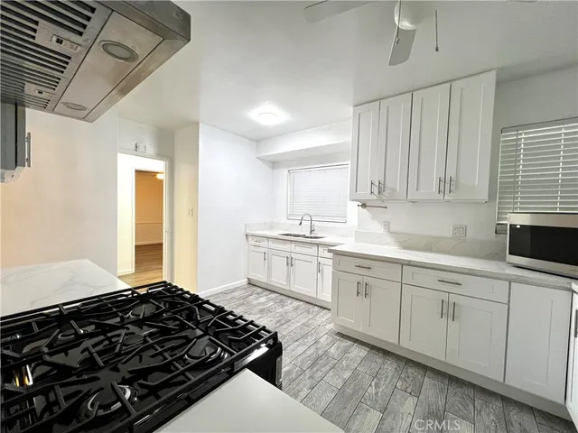 a kitchen with a stove a sink and white cabinets