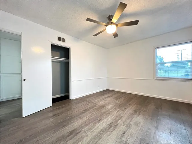 an empty room with wooden floor chandelier fan and windows