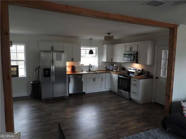 a kitchen with granite countertop stainless steel appliances a sink a refrigerator a stove a microwave and cabinets