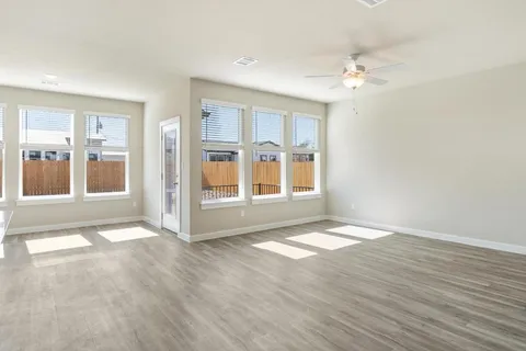 a view of an empty room with glass door and wooden floor