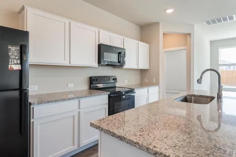 a kitchen with stainless steel appliances granite countertop a sink a stove and a refrigerator with white cabinets