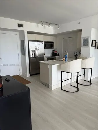 a living room with stainless steel appliances kitchen island granite countertop a sink a stove and a refrigerator