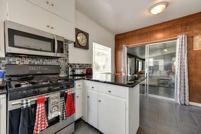 a view of a patio with a table and chairs under an umbrella with a barbeque