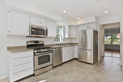a kitchen with cabinets stainless steel appliances and a window
