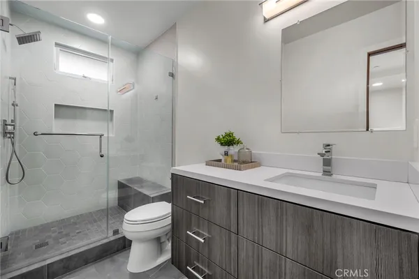 a bathroom with a granite countertop sink toilet a mirror and shower
