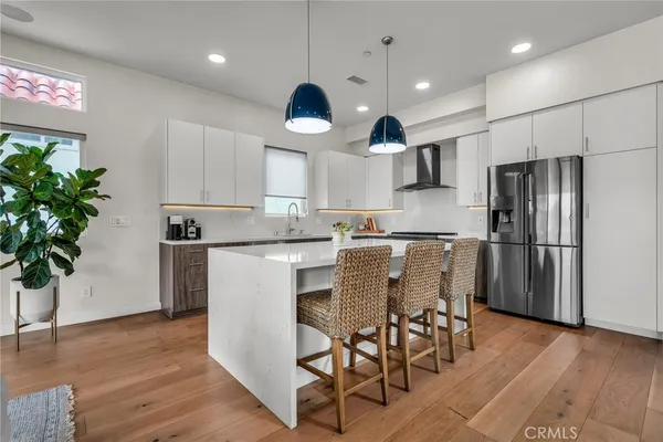a kitchen with stainless steel appliances granite countertop a refrigerator a stove a sink dishwasher and a dining table with wooden floor