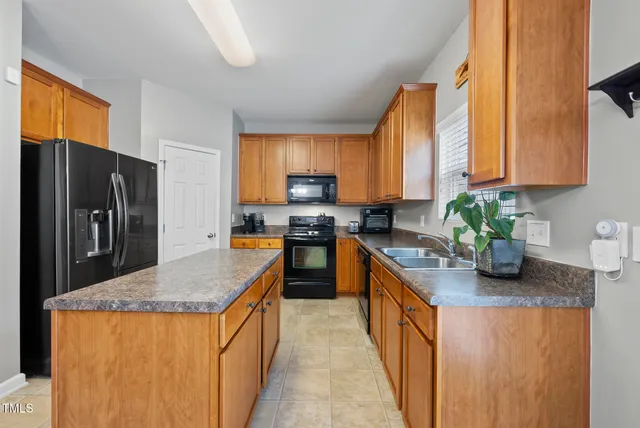 a kitchen with kitchen island granite countertop a sink a counter top space and stainless steel appliances