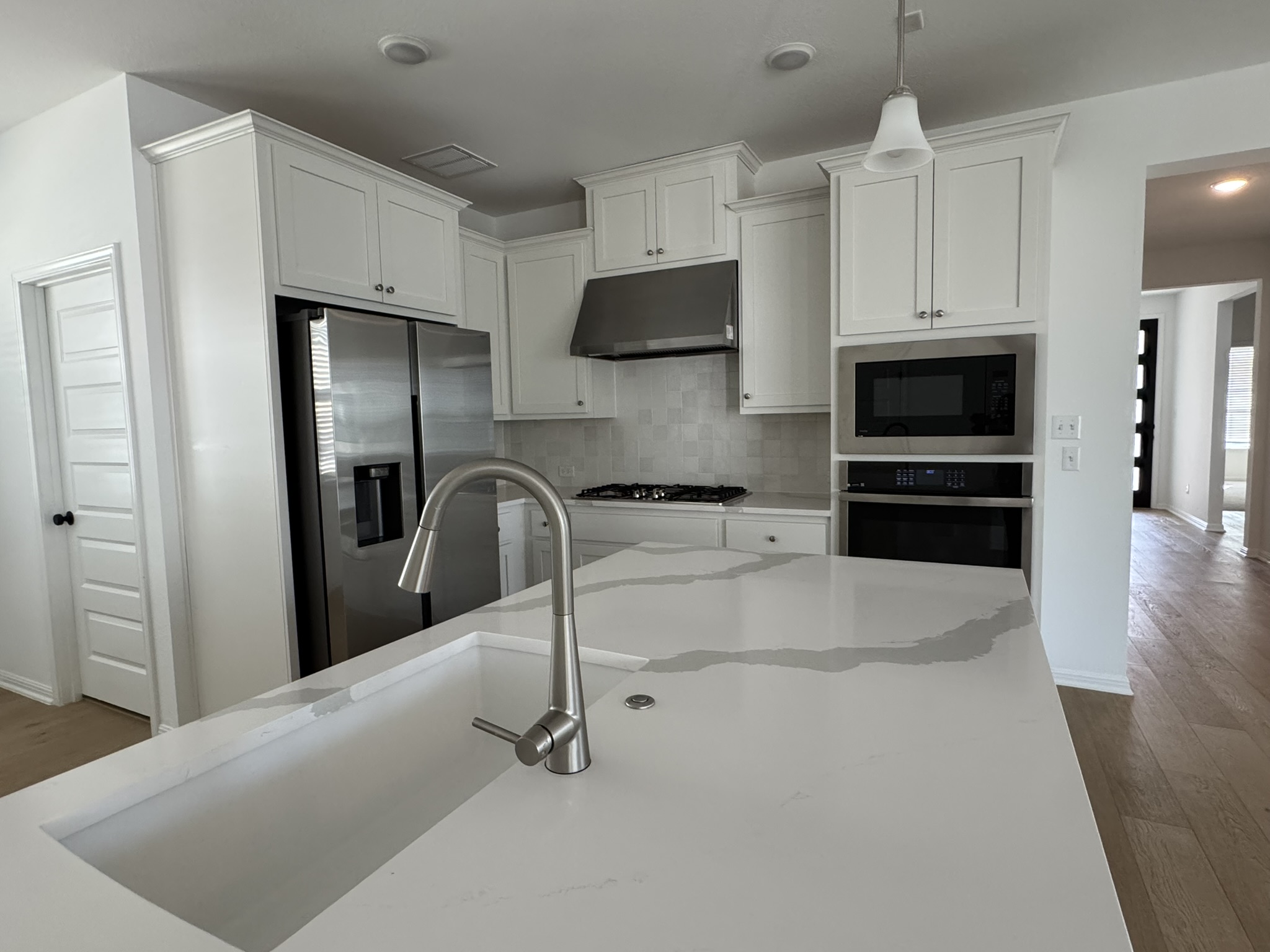 4500 Modena Bend Leander, TX 78641 - Photo 2 of 22 Kitchen featuring dark wood-style floors, white cabinets, stainless steel appliances, decorative backsplash, and light stone countertops