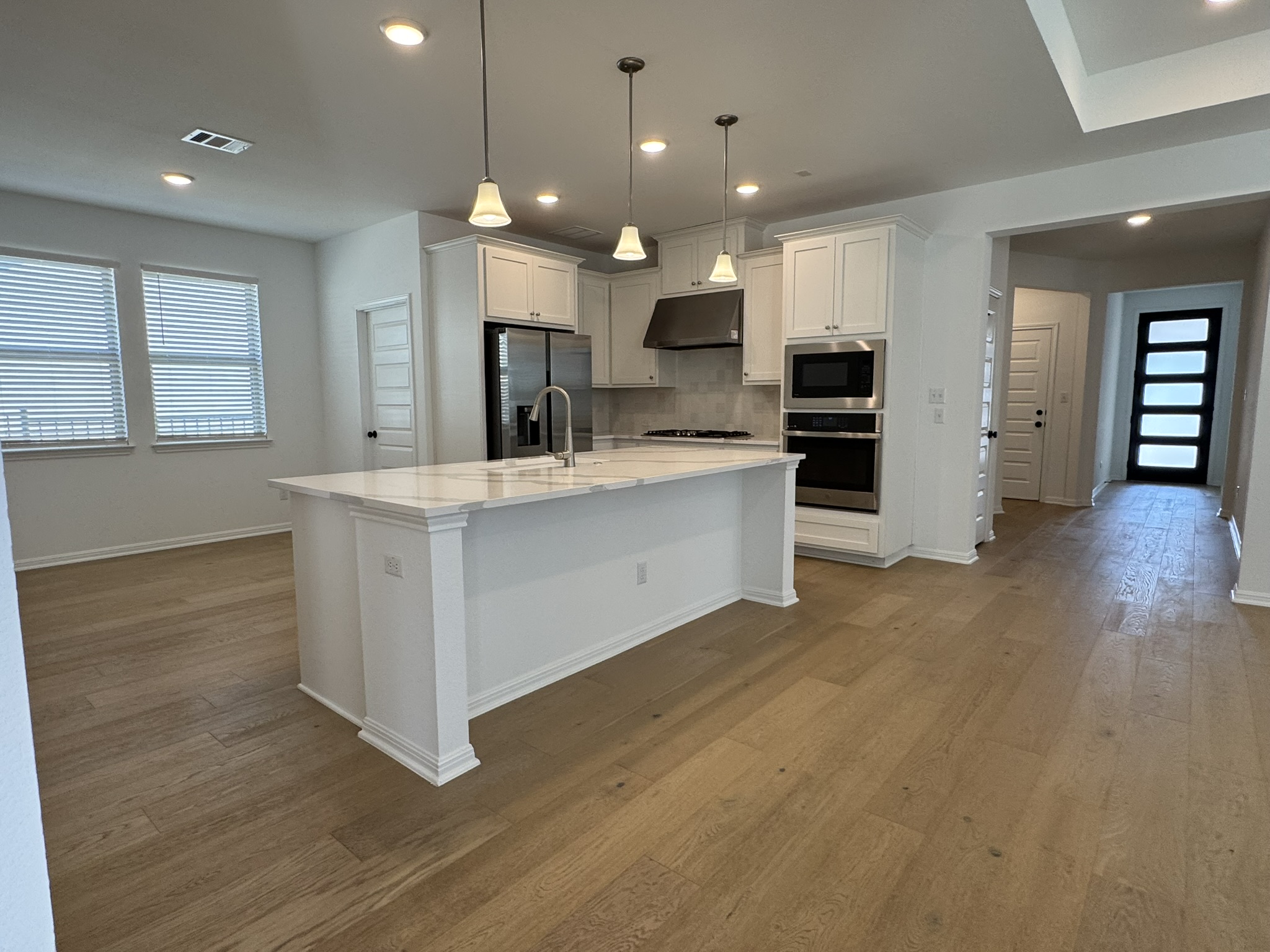 4500 Modena Bend Leander, TX 78641 - Photo 3 of 22 Kitchen with healthy amount of natural light, white cabinets, dark wood finished floors, and a center island with sink