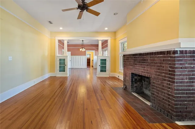 a view of a livingroom with wooden floor a fireplace and windows