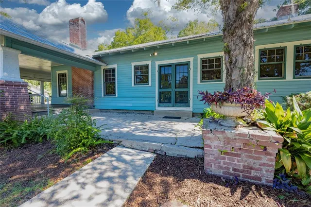 a front view of a house with a yard and potted plants