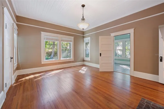 a view of an empty room with wooden floor fireplace and a window
