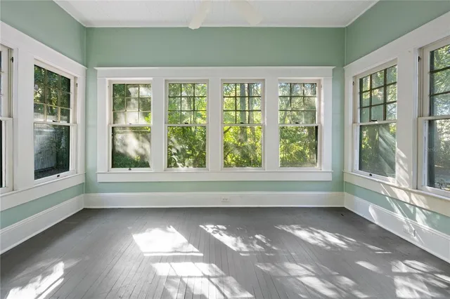 a view of an empty room with a window and wooden floor