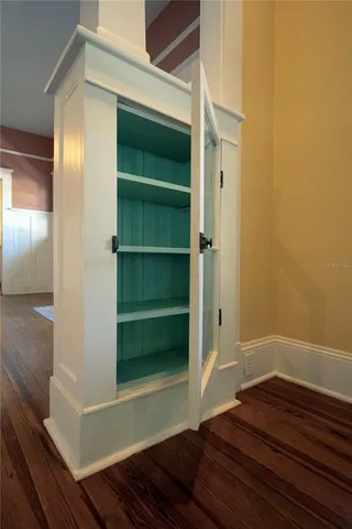 a view of an empty room with wooden floor and windows