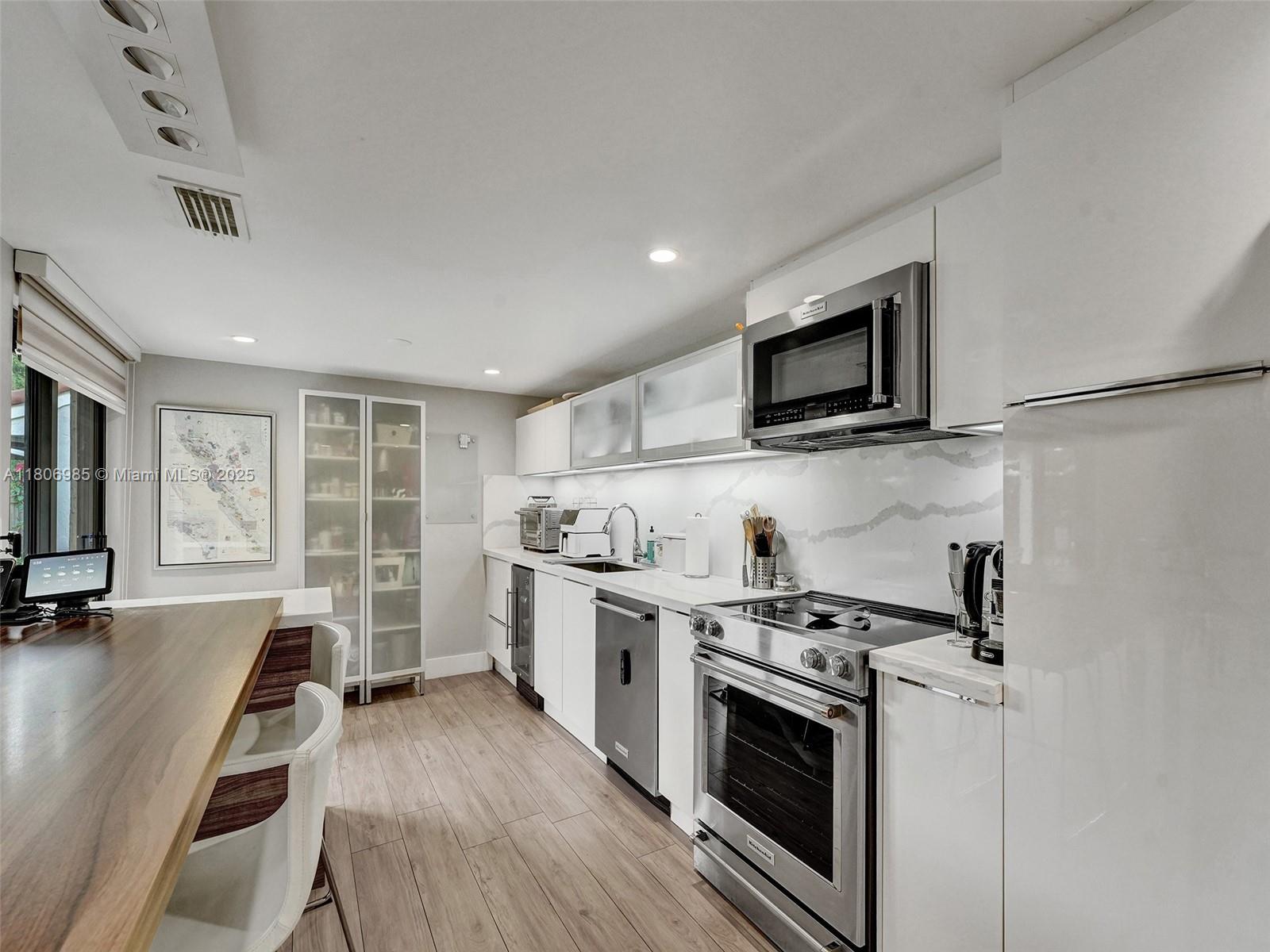 3638 Southwest 57th Avenue Miami, FL 33155 - Photo 8 of 43 a kitchen with stainless steel appliances a stove top oven a sink dishwasher a refrigerator and white cabinets with wooden floor