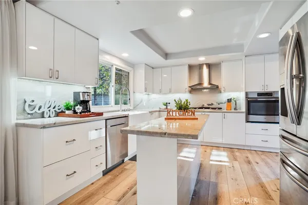 a dining room with stainless steel appliances granite countertop furniture a chandelier and wooden floor