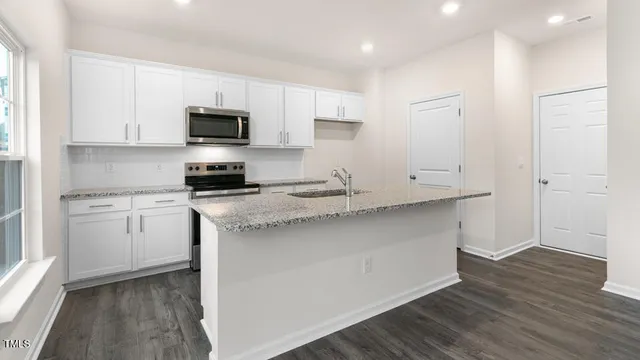 a kitchen with granite countertop white cabinets and stainless steel appliances