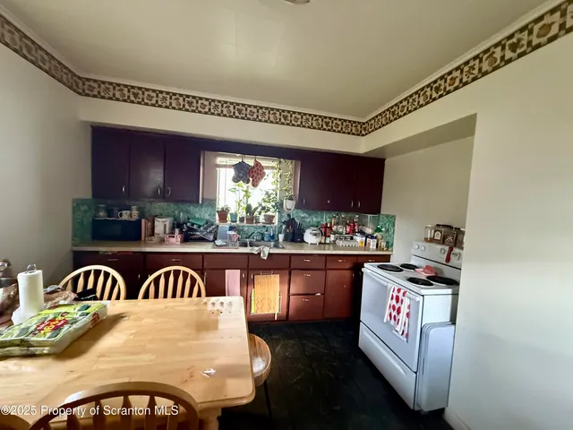 a view of a kitchen with kitchen island granite countertop a stove a sink dishwasher with a dining table