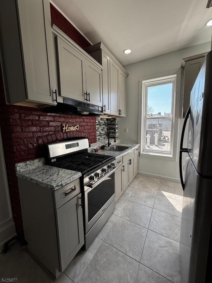 48 Market Street Paterson, NJ 07505 - Photo 5 of 8 a kitchen with stainless steel appliances granite countertop a stove a refrigerator and a microwave