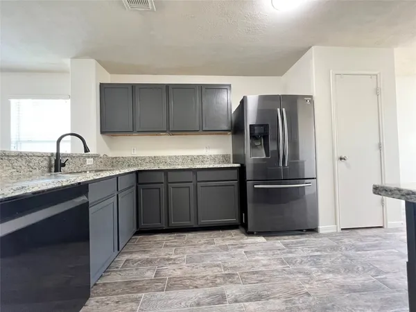 a kitchen with granite countertop a refrigerator and a sink