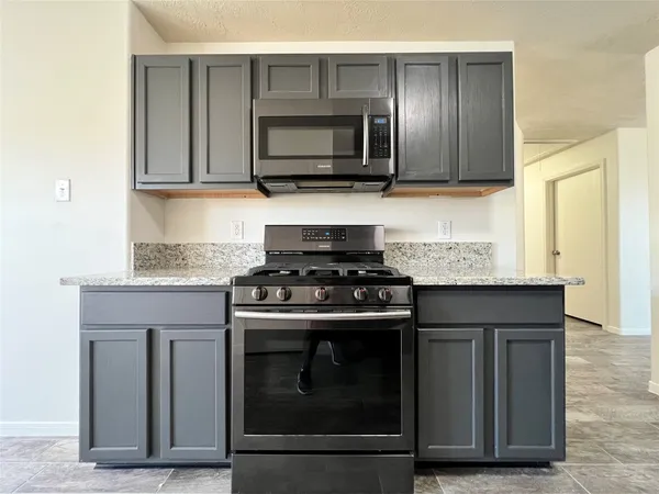 a kitchen with granite countertop a stove and a microwave