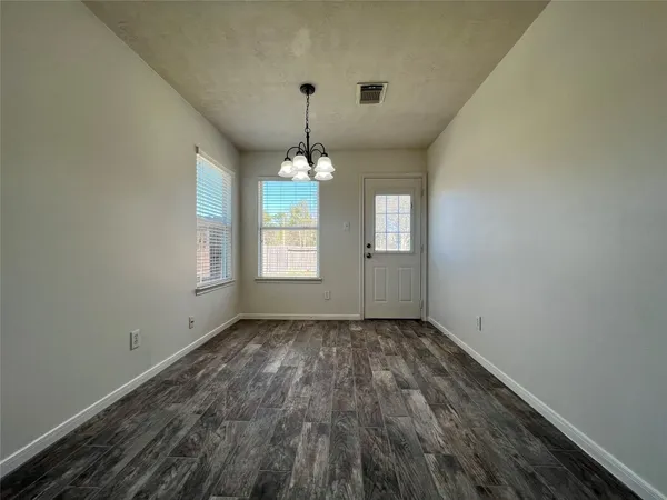 an empty room with chandelier fan and windows