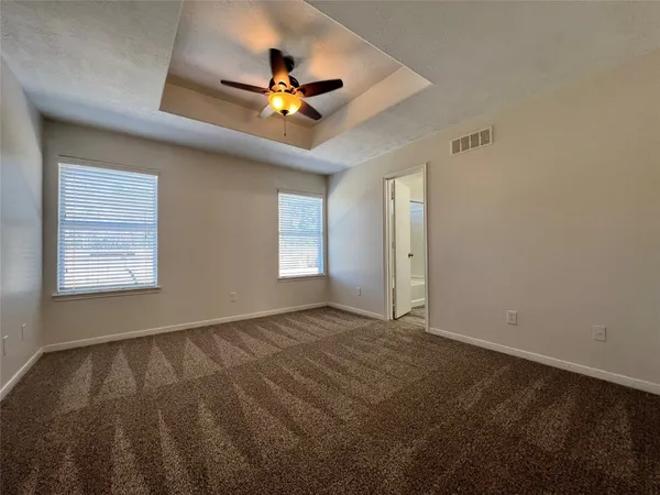 a view of an empty room with window and chandelier fan