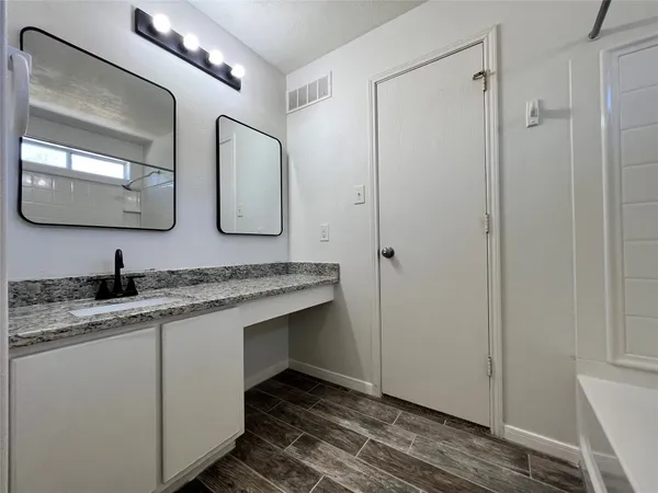 a bathroom with a granite countertop sink a mirror and shower