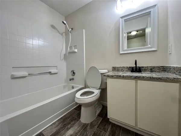 a bathroom with a granite countertop toilet sink and mirror