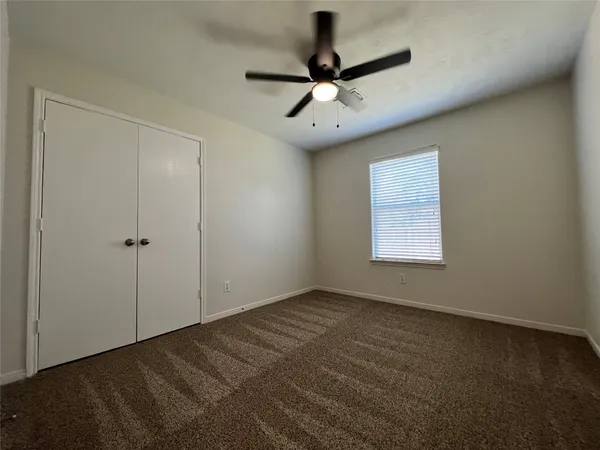an empty room with a window and a fan